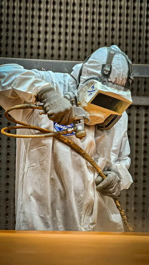 Industrial worker performing high-pressure hydroblasting at a refinery site.